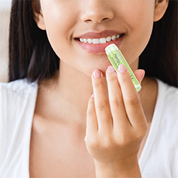 Woman putting on Blistex Hemp and Shea hydration lip balm